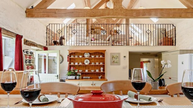 Comedor con una olla roja, copas de vino y una mesa de madera.