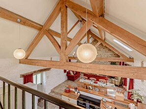 Een ruime loft met zichtbare houten balken, een keukenhoek en een eethoek.