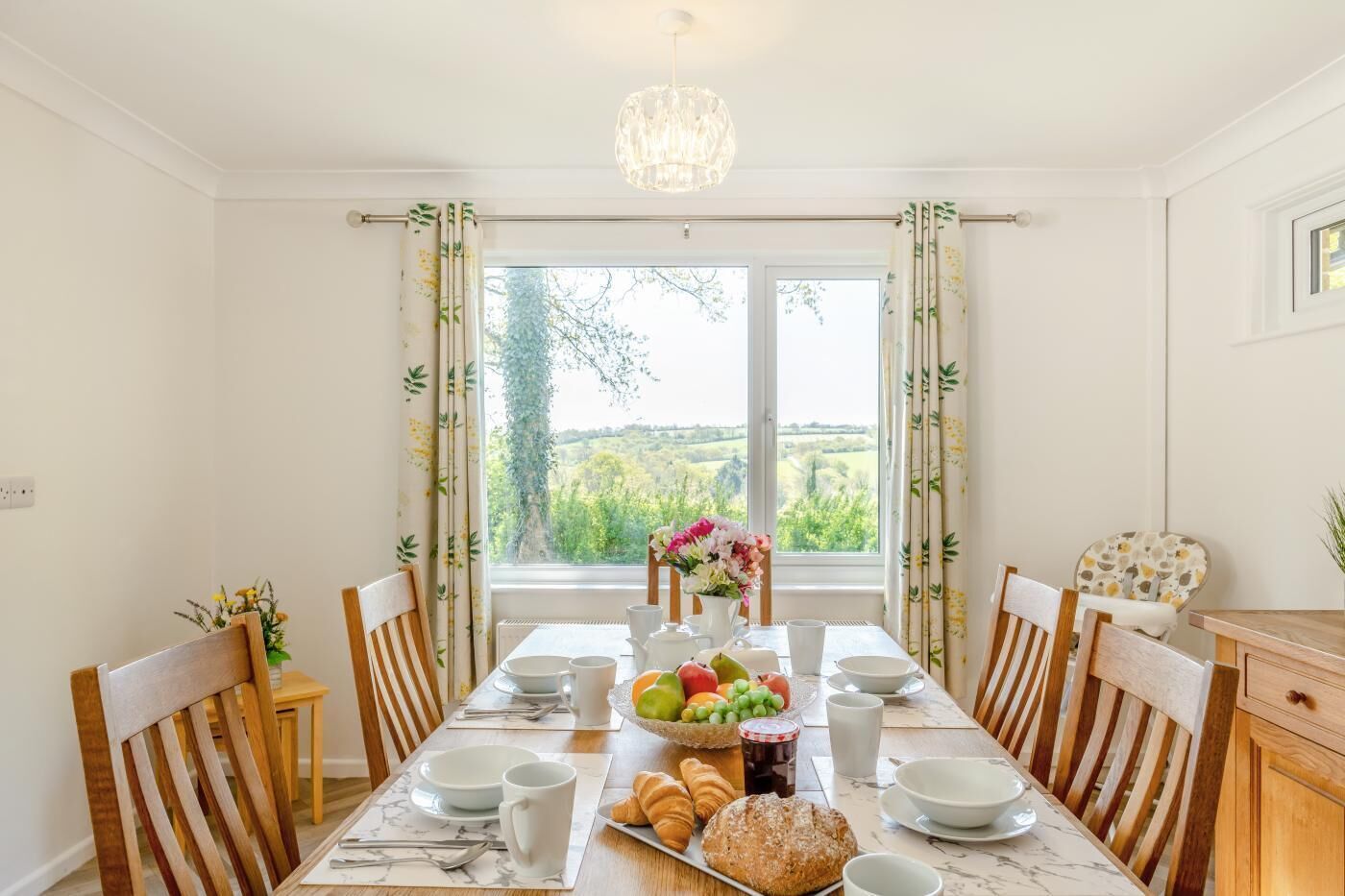 A dining room with a table set for breakfast, including bread, fruit, and beverages.