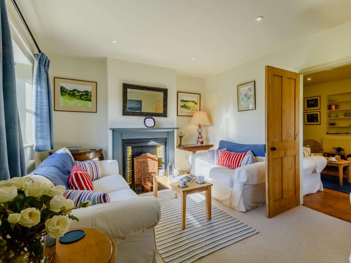 A living room with a fireplace, two sofas, a coffee table, and a door leading to another room.