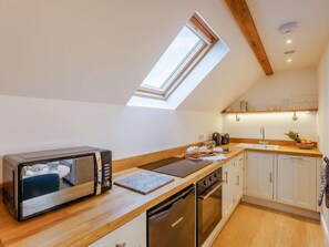 Eine Küche mit Oberlicht, einer Mikrowelle, einem Toaster, einer Kaffeemaschine und einem Geschirrspüler.