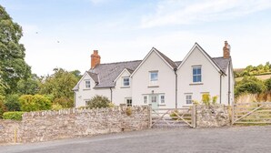 A white two-story house with a stone wall and a wooden gate. - 5 Bed in Crickhowell (oc-90053) (Glangrwyney)