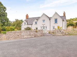 A white two-story house with a stone wall and a wooden gate. - 5 Bed in Crickhowell (oc-90053) (Glangrwyney)