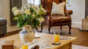 A wooden table with a vase of flowers, a glass of orange juice, and a book. - 5 Bed in Crickhowell (oc-90053) (Glangrwyney)