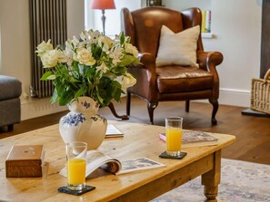 A wooden table with a vase of flowers, a glass of orange juice, and a book. - 5 Bed in Crickhowell (oc-90053) (Glangrwyney)