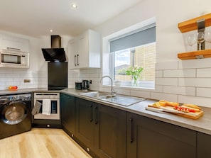 A modern kitchen with a built-in oven, microwave, and dishwasher. - 2 Bed in Chathill (oc-90017) (Beadnell)