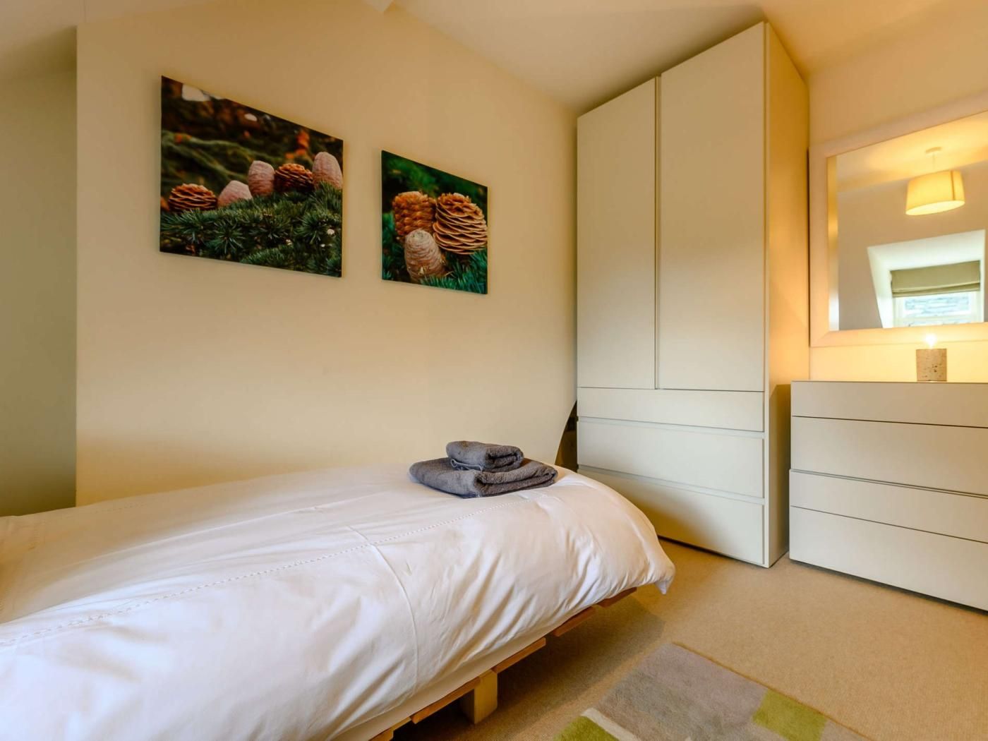 Une chambre à coucher avec un lit, une commode et deux tableaux encadrés accrochés au mur.