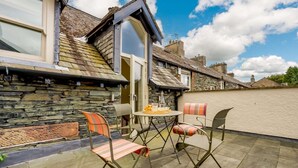 A patio with stone flooring, a table, and chairs. - 4 Bed in Keswick (oc-89258) (Keswick)
