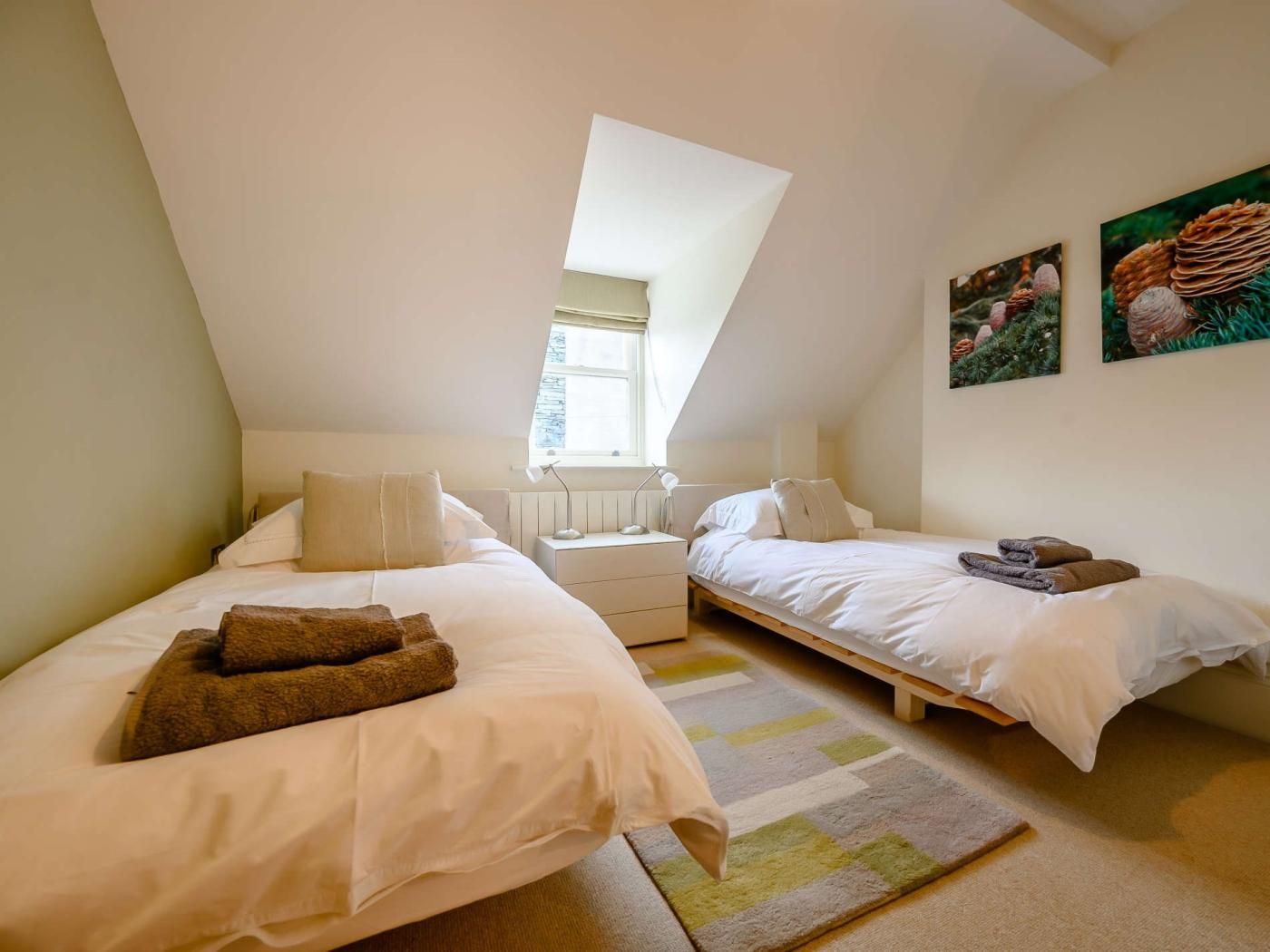 Een slaapkamer met twee bedden, een raam en een schilderij.