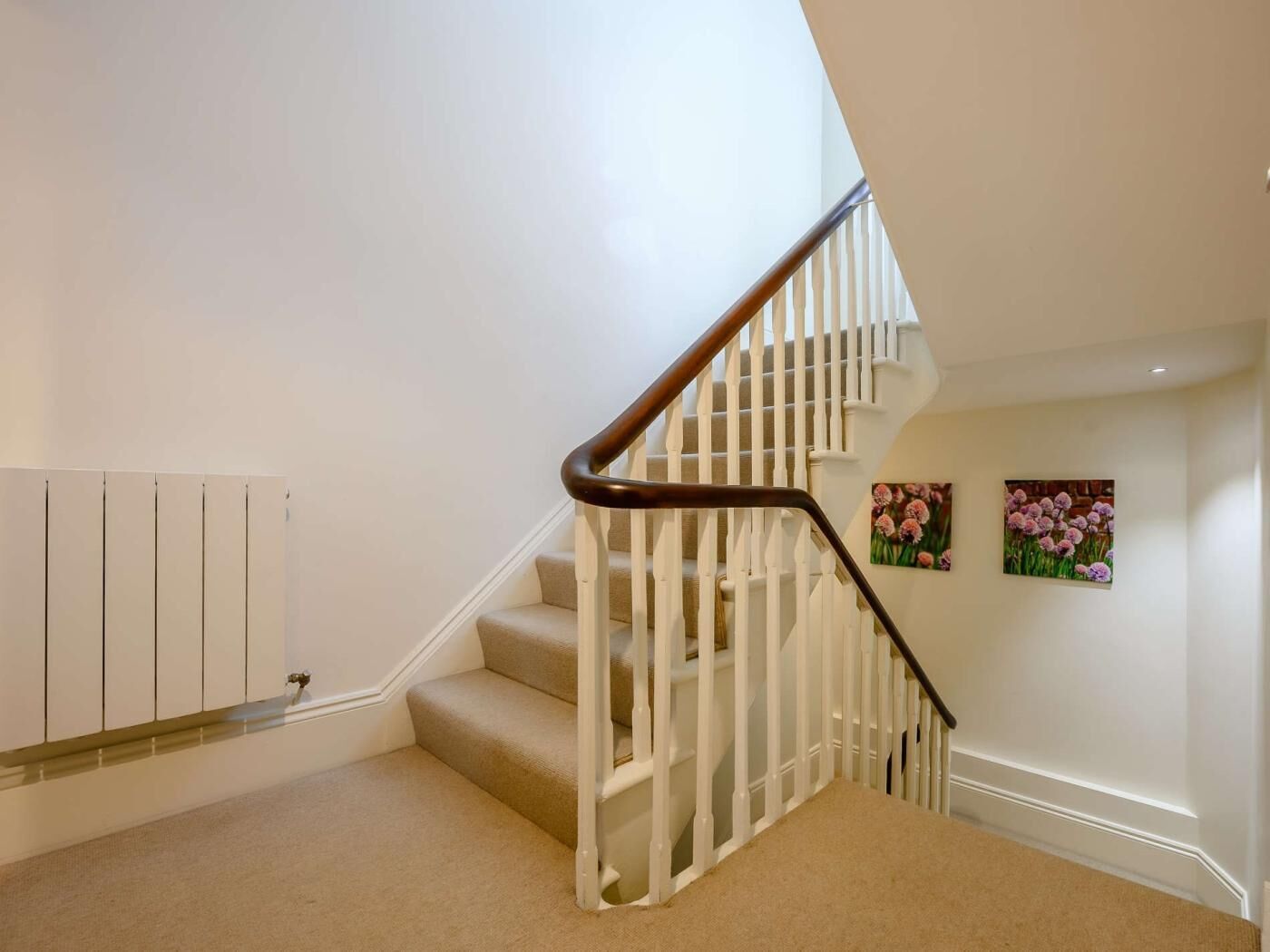 A staircase with white railings and beige carpet.