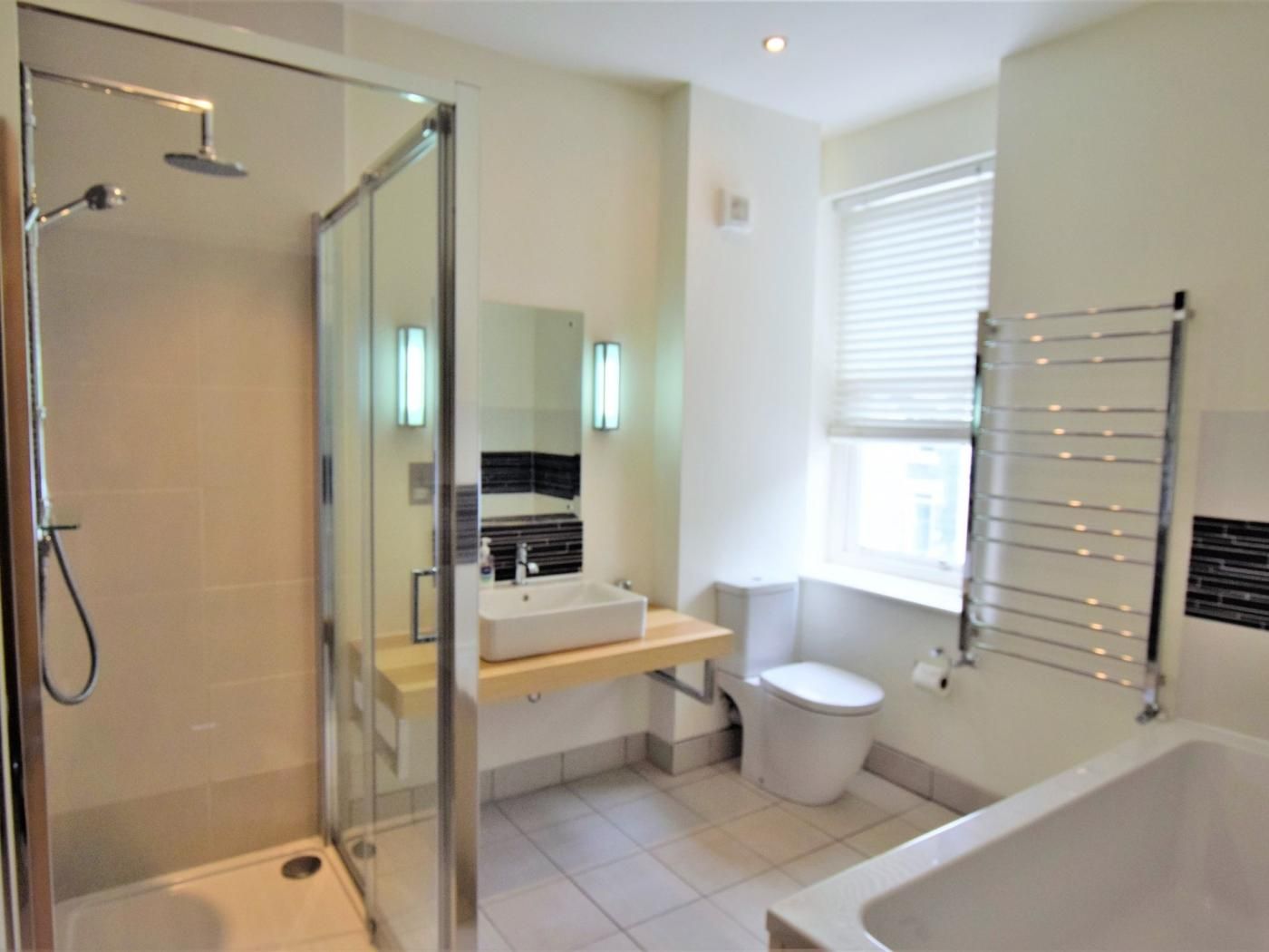 A bathroom with a glass-enclosed shower, a sink with a mirror, a toilet, and a bathtub.