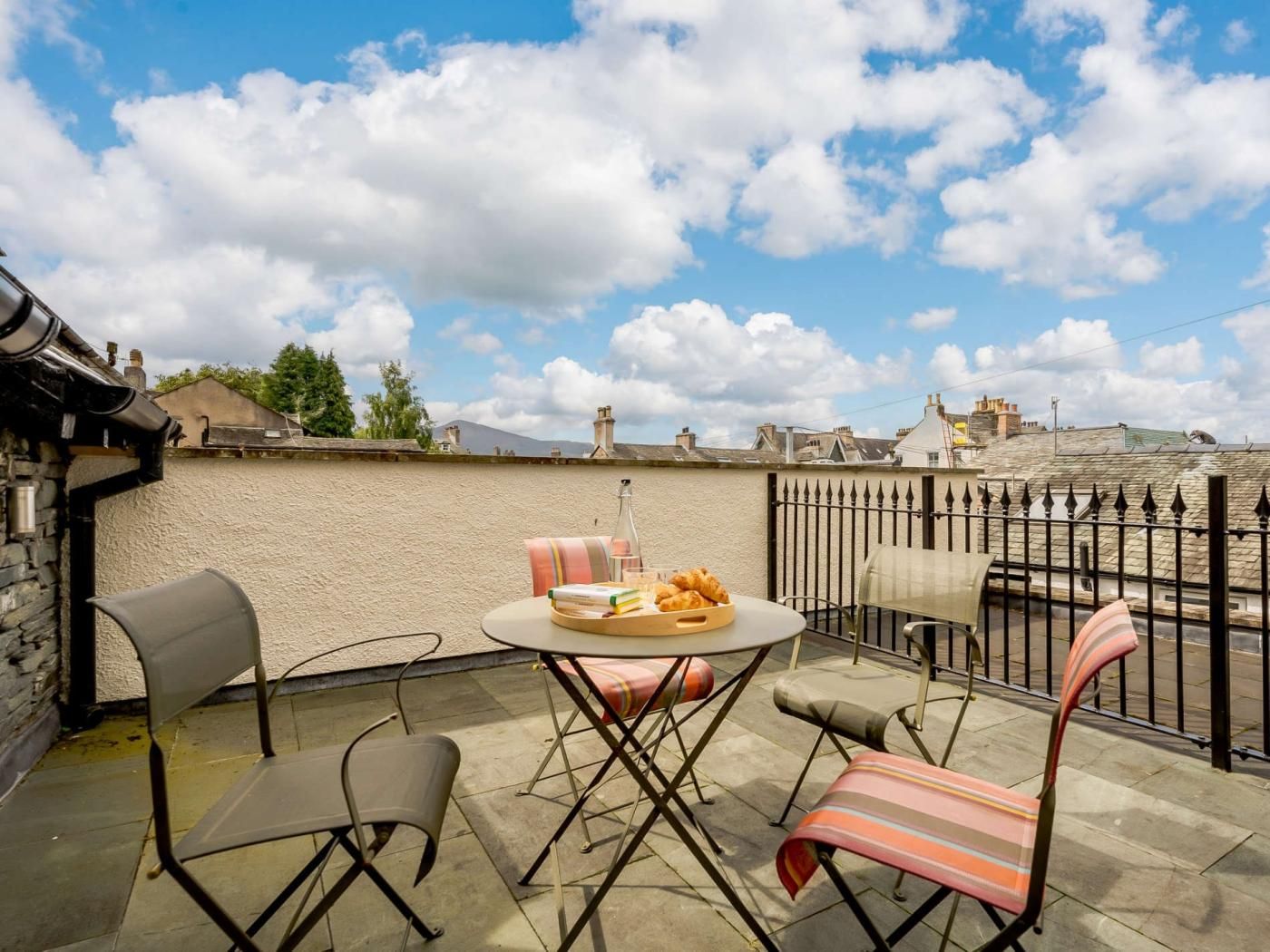 Une terrasse avec une table ronde, deux chaises et un barbecue.