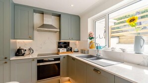 A modern kitchen with built-in appliances, a large window with a view, and a minimalist design. - 4 Bed in Newquay (oc-89241) (Newquay)