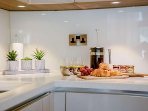 A kitchen counter with a coffee maker, a plate of croissants, and a glass of orange juice. - 2 Bed in Keswick (oc-89261) (Portinscale)