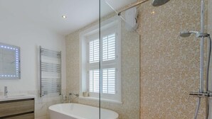 Een moderne badkamer met een vrijstaand bad, een douchecabine met glazen wanden en een wastafel met spiegel.