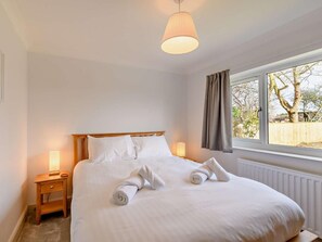 A neatly made bed with pillows and rolled towels, a bedside table with a lamp, and a window with curtains. - 4 Bed in Alnwick (oc-89964) (Christon Bank)