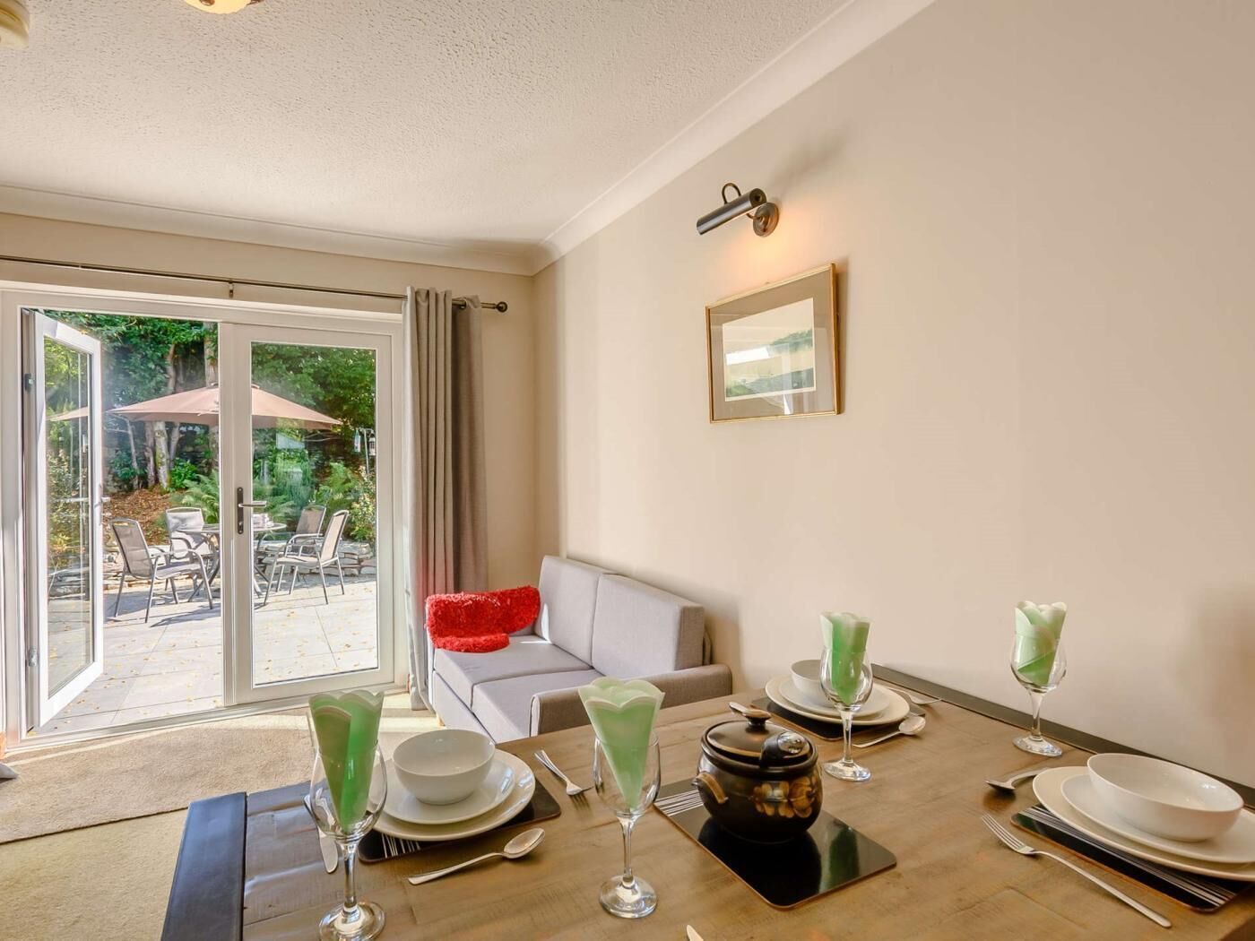 A dining area with a table set for four, a sofa, and a sliding glass door leading to an outdoor patio.