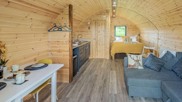 A cozy, wooden interior with a dining area, kitchen, and a sofa with patterned cushions. - 1 Bed in Holsworthy (oc-89791) (Holsworthy Hamlets)