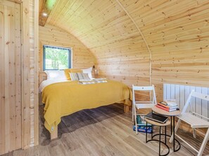 A cozy room with a bed, a small table, and a window.