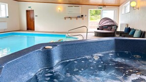 Un bain à remous, une piscine et un espace détente avec des coussins.
