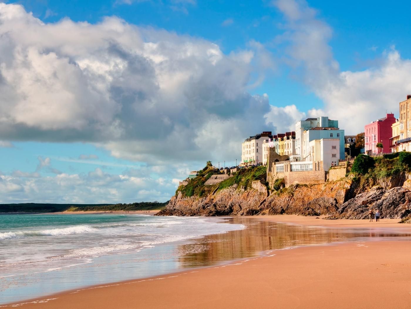 A coastal beach with buildings on a cliff overlooking the sea.