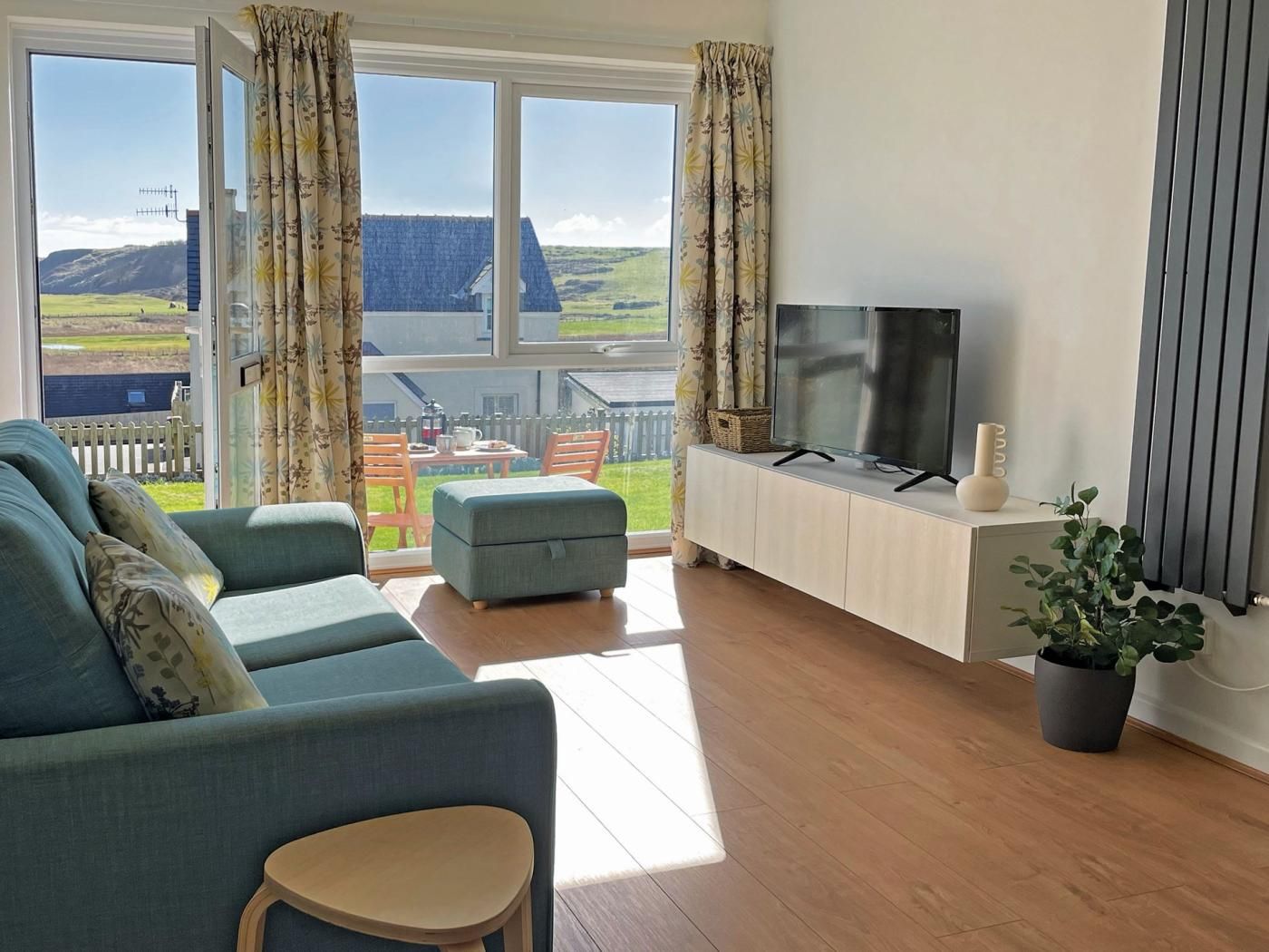 A living room with a sofa, a television, and a potted plant.