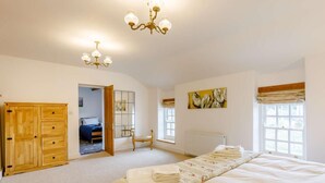 A bedroom with a large bed, a wooden wardrobe, a mirror, a radiator, and a chandelier. - 3 Bed in Coleford (oc-89806) (Coleford)