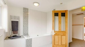 A bathroom with a bathtub, a towel rack, and a shower area. - 3 Bed in Coleford (oc-89806) (Coleford)