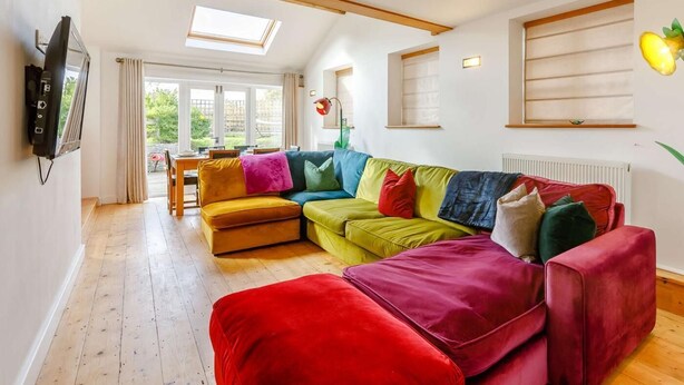 A modern living room with a sectional sofa, a dining area, and skylights. - 3 Bed in Coleford (oc-89806) (Coleford)