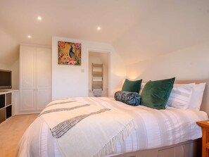 A bedroom with a bed, a TV, a wardrobe, and a painting on the wall. - 3 Bed in Cheltenham (oc-89850) (Bourton-on-the-Water)