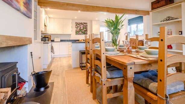 A cozy kitchen with wooden beams, a dining table set for four, and a fireplace. - 3 Bed in Cheltenham (oc-89850) (Bourton-on-the-Water)