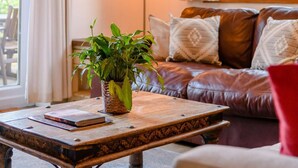 A cozy living room with a leather sofa, a wooden coffee table, and a potted plant. - 3 Bed in Cheltenham (oc-89850) (Bourton-on-the-Water)