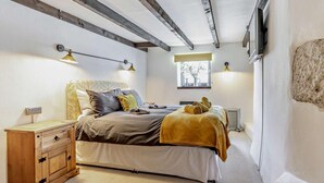 Een slaapkamer met een bed, nachtkastje, lamp, raam en radiator.
