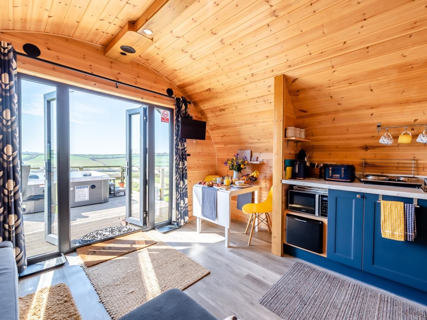 Ein modernes Blockhaus mit Essbereich, Küche und einer Glastür, die auf eine Außenterrasse führt.