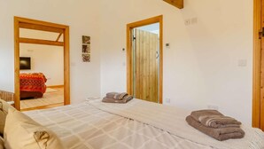 Ein Schlafzimmer mit Bett, Holzbalke, einer Tür und einem Spiegel.