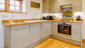Eine Küche mit Holzausziehtisch, Spüle, Toaster, Backofen und hellen Schränken.