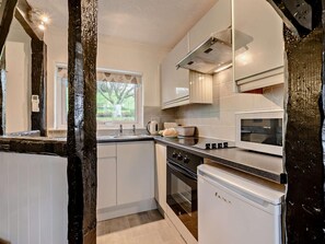A modern kitchen with white cabinetry, a built-in oven, and a microwave. - 1 Bed in Looe (oc-90170) (Trenewan)