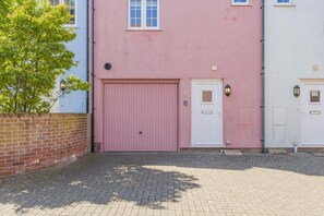 A building with a pink garage door, a white door, and a small window. - 2 Bed in Cromer (oc-90187) (Cromer)