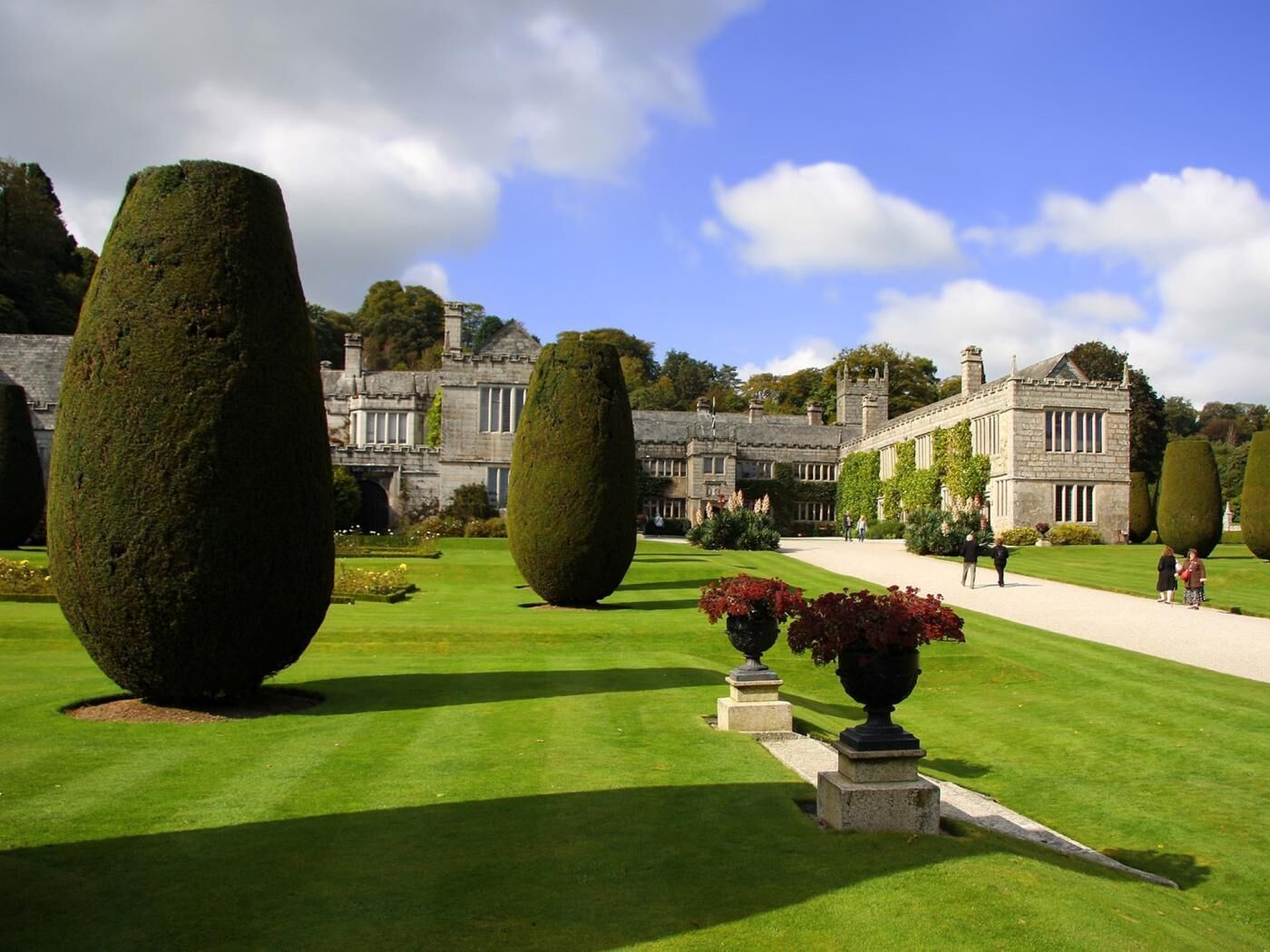 A formal garden with neatly trimmed hedges and a historic building with stone architecture.