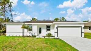 A single-story house with a garage, a front lawn, and a clear sky.
