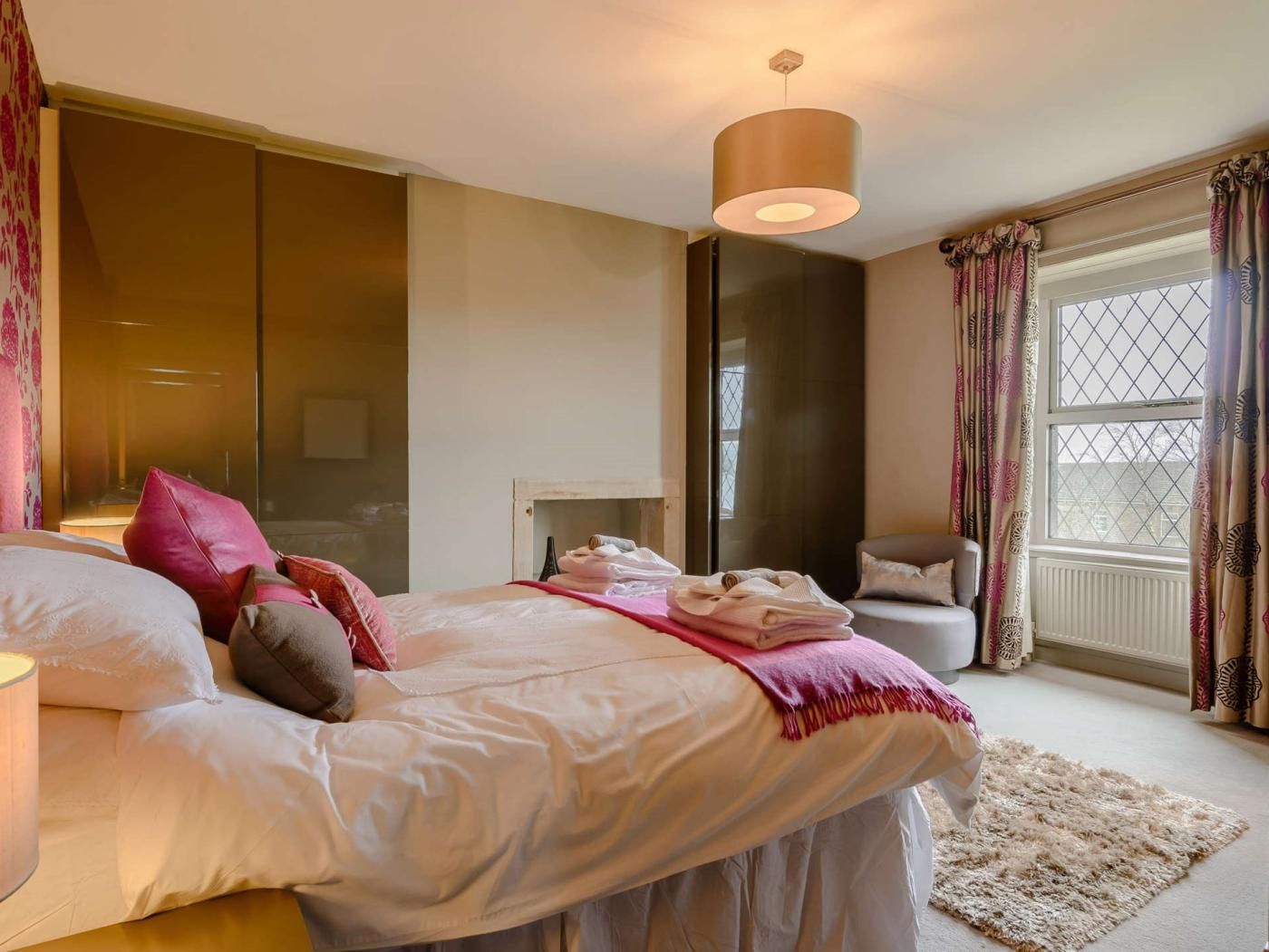 A bedroom with a bed, bedside table, lamp, and a window with curtains.