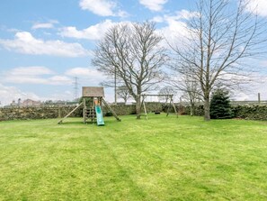 A grassy outdoor area with a wooden play structure including a slide and swings. - 3 Bed in Halifax (oc-90209) (Sowerby Bridge)