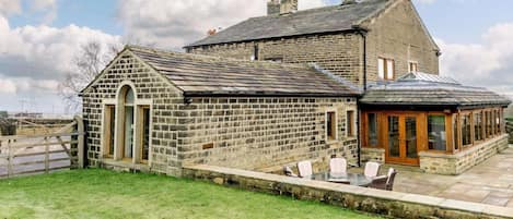 A stone house with a large patio area and a conservatory.