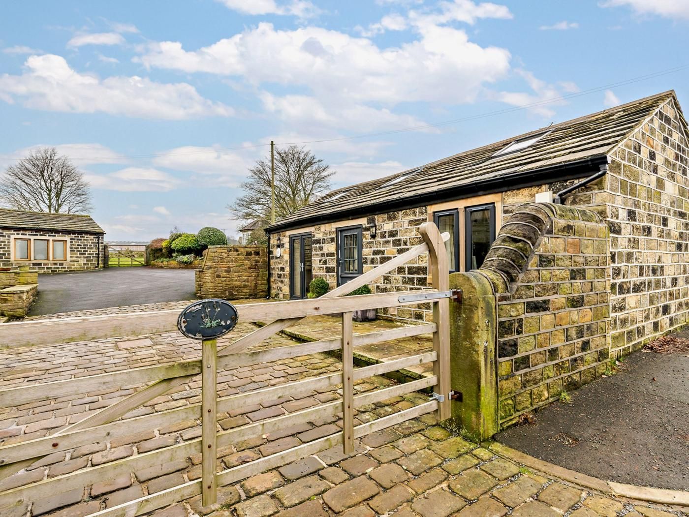 A stone building with a wooden gate and steps leading to a driveway.