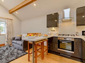 Eine moderne Küche mit Einbauofen, eine Essecke mit Tisch und Stühlen sowie ein graues Sofa.