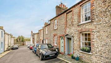 A row of stone houses with parked cars on a residential street.