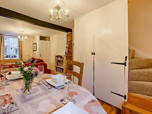A dining area with a table set for four, a vase of flowers, and a bookshelf in the background. - 2 Bed in Arundel (oc-89671) (Arundel)