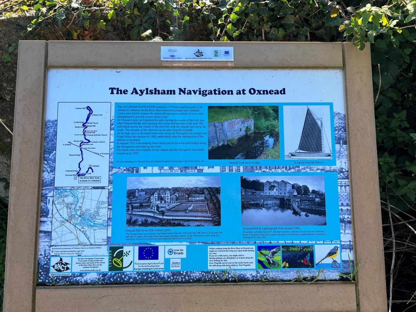 Tabella informativa su The Aylsham Navigation a Oxnead, con mappe storiche, fotografie e dettagli sullo sviluppo della zona.