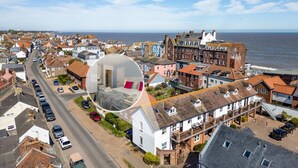 Une ville côtière aux bâtiments d’architecture traditionnelle, un hôtel imposant reconnaissable à son enseigne, et une vue dégagée sur la mer.