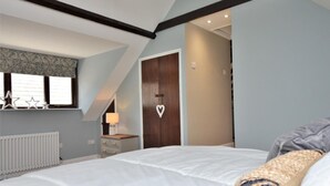 Un dormitorio con una cama, una mesita de noche, una lámpara, un radiador, una ventana con adornos de estrellas y un adorno con forma de corazón en la puerta.